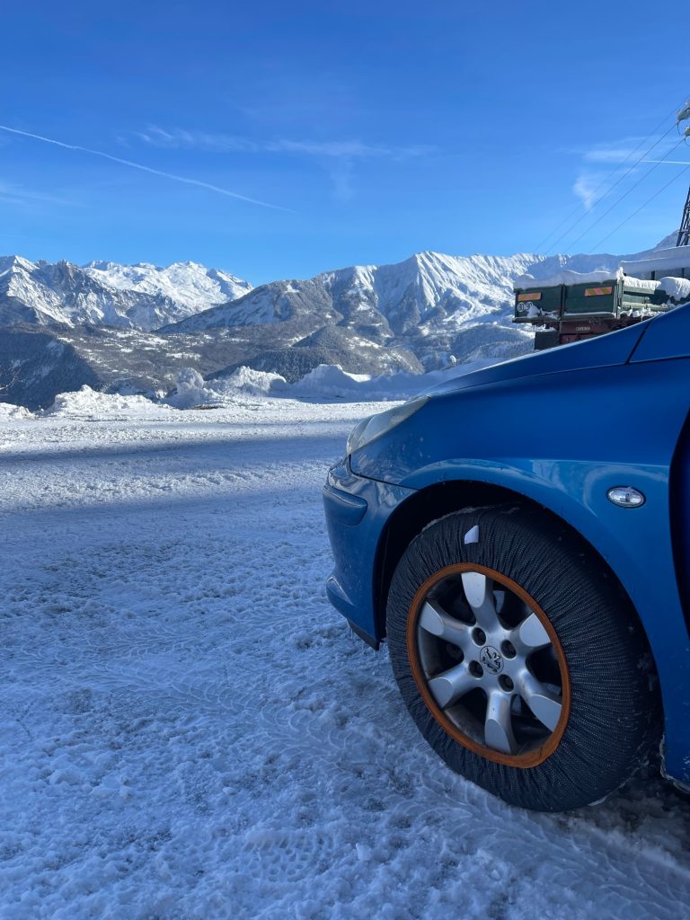Peugeot 307 avec chaussette à neige Rescal face aux montagnes enneigées