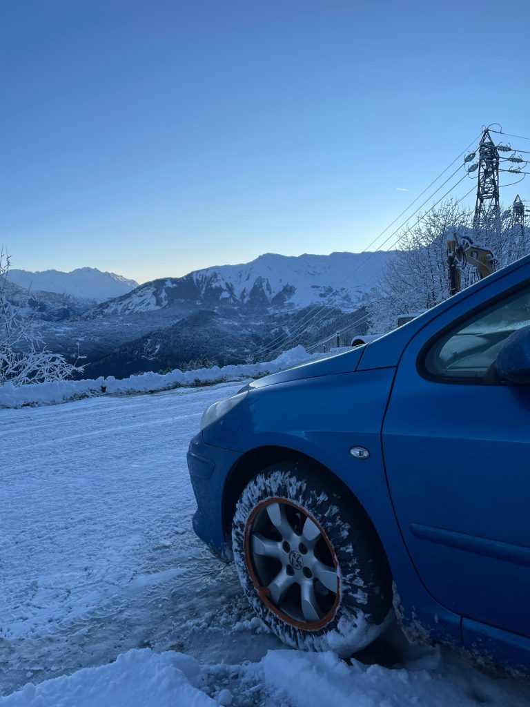 Peugeot 307 avec chaussette à neige Rescal sur route enneigée à l’aube